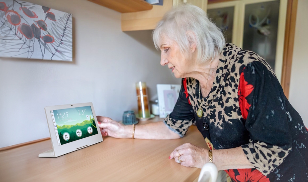 Elder woman checking her indoor air quality on an L-shaped tablet resting on her kitchen countertop